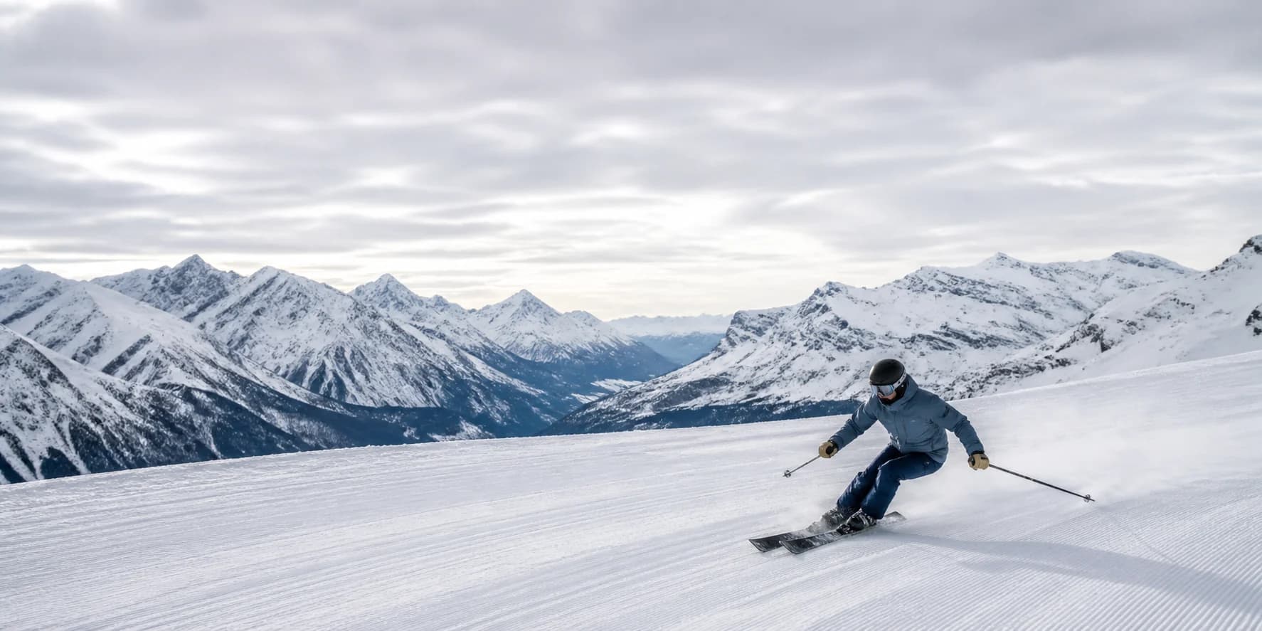 Alpine skier carving across a groomed mountain run