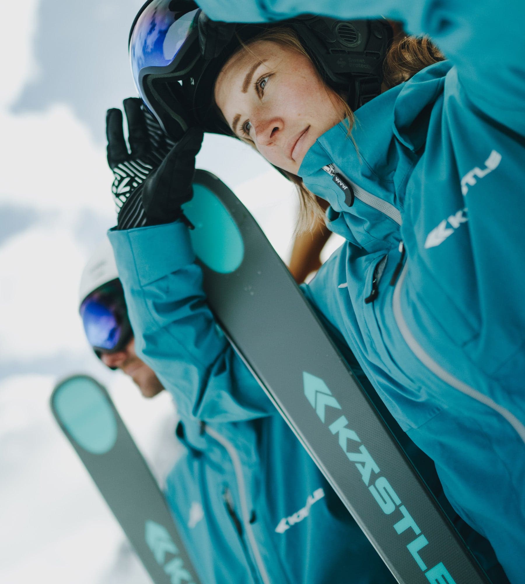 Skiers carrying Kästle skis on a winter day